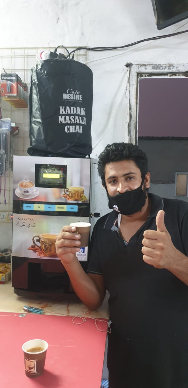 Retail staff serving Café Desire karak from a showroom counter